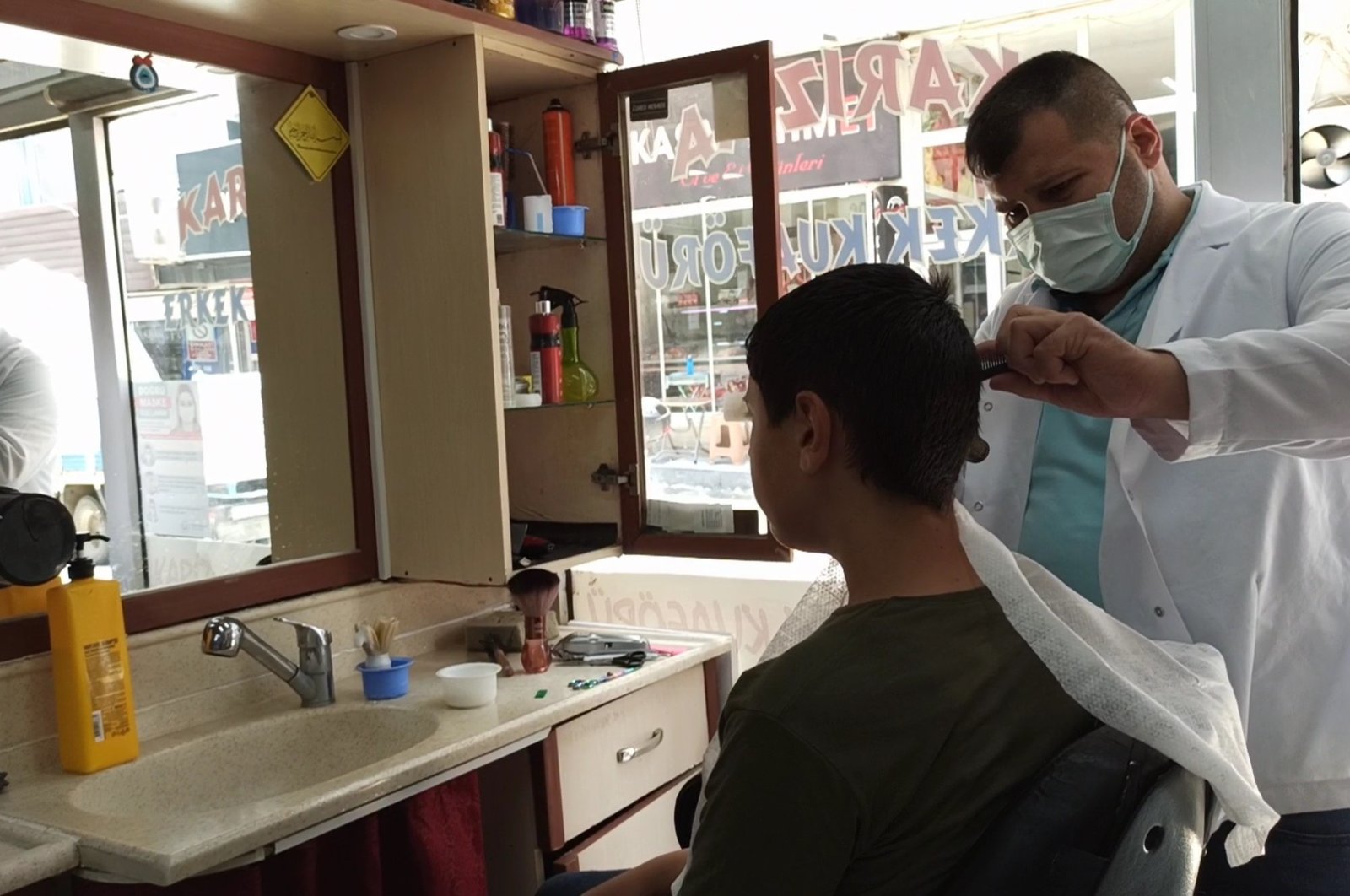 A barber cuts his customers' hair in a barbershop in the northwestern province of Edirne, Turkey, June 28, 2021. (IHA Photo)