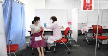 A cabin crew member (L) of Japan Airlines receives the Moderna vaccine for COVID-19 on the first day of the company's workplace vaccination campaign at Haneda Airport in Tokyo, Japan, June 14, 2021. (AFP Photo)
