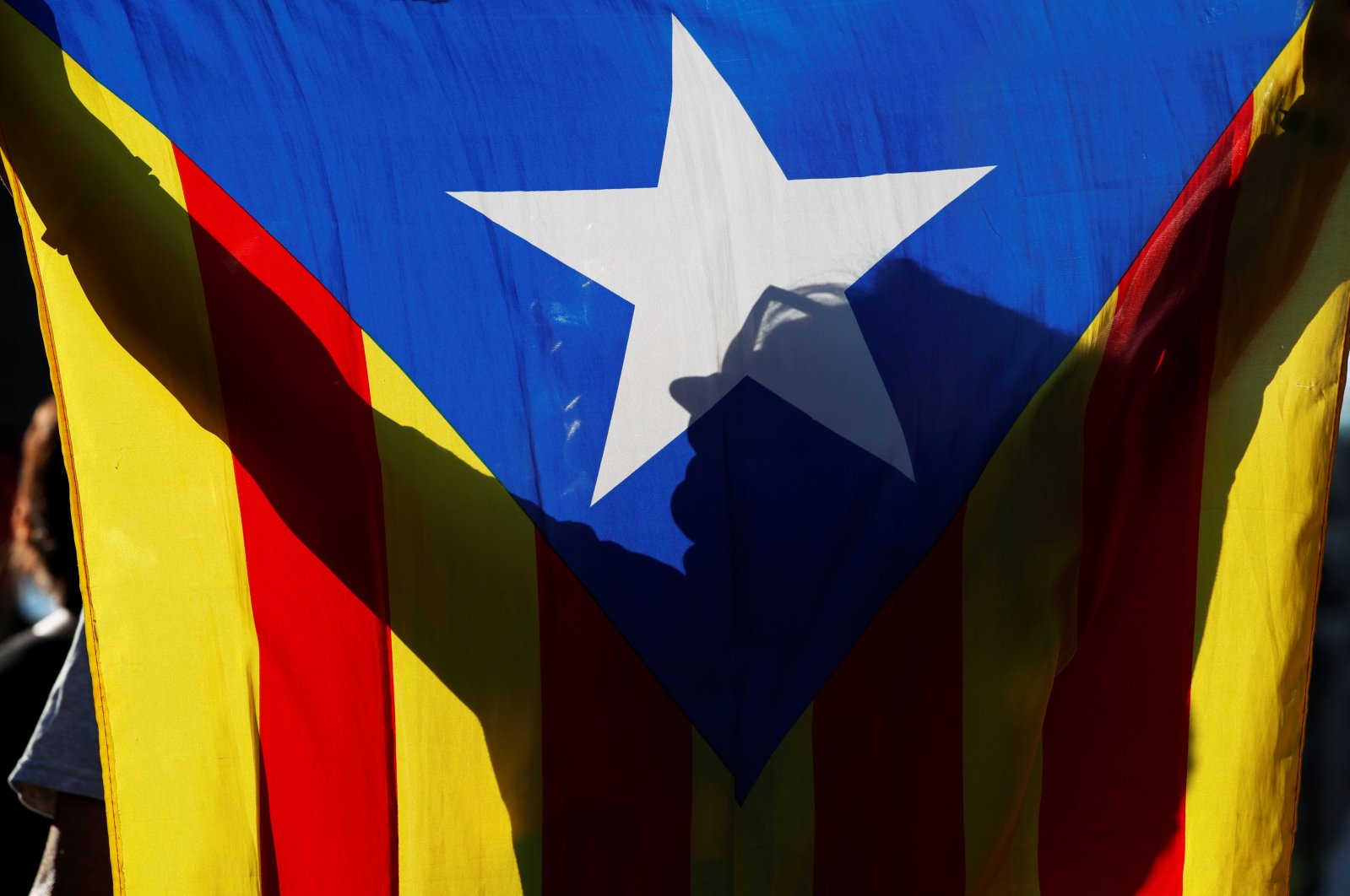 A woman is silhouetted in an Estelada flag (the Catalan pro-independence flag) during a protest called by separatist Committee for the Defense of the Republic (CDR) against Spain's King Felipe VI visit at the Mobile World Congress inaugural dinner, in Barcelona, Spain, June 27, 2021. (Reuters Photo)
