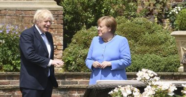Britain's Prime Minister Boris Johnson (L) and German Chancellor Angela Merkel, walk through the garden at Chequers, the country house of the Prime Minister, in Buckinghamshire, England, July 2, 2021. (AP Photo)