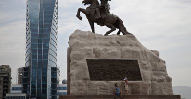Mongolian children play near a statue of Damdin Sukhbaatar, leader of Mongolia’s 1921 revolution at Sukhbaatar Square in Ulan Bator, Mongolia, July 2, 2012. (AP Photo)
