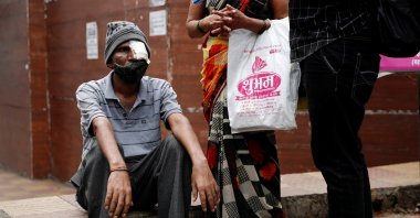 Shivaji Veer (L), 51, a school bus driver, accompanied by his wife Vimal Veer 46, waits to board a taxi to go home after a follow-up consultation at a hospital after losing his eye due to Mucormycosis, also known as black fungus, in Pune, India, July 1, 2021. (Reuters Photo)
