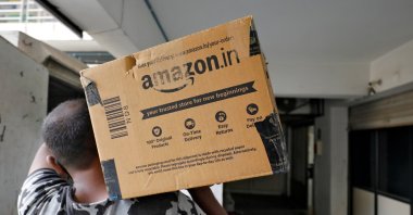 A delivery worker carries an Amazon package to deliver it to a customer at a residential apartment in Ahmedabad, India, March 17, 2021. (Reuters Photo)