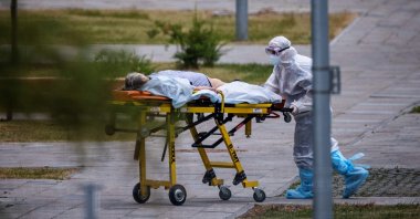 A medic wheels a woman into a hospital where patients infected with the coronavirus are being treated in the settlement of Kommunarka, outside Moscow, Russia, June 30, 2021. (AFP Photo)
