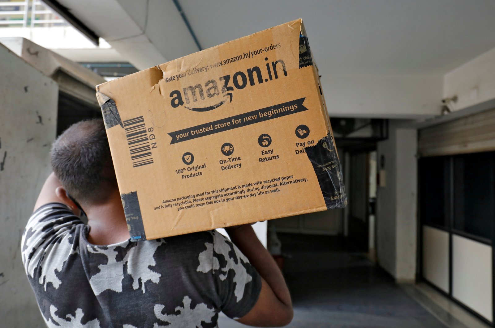 A delivery worker carries an Amazon package to deliver it to a customer at a residential apartment in Ahmedabad, India, March 17, 2021. (Reuters Photo)