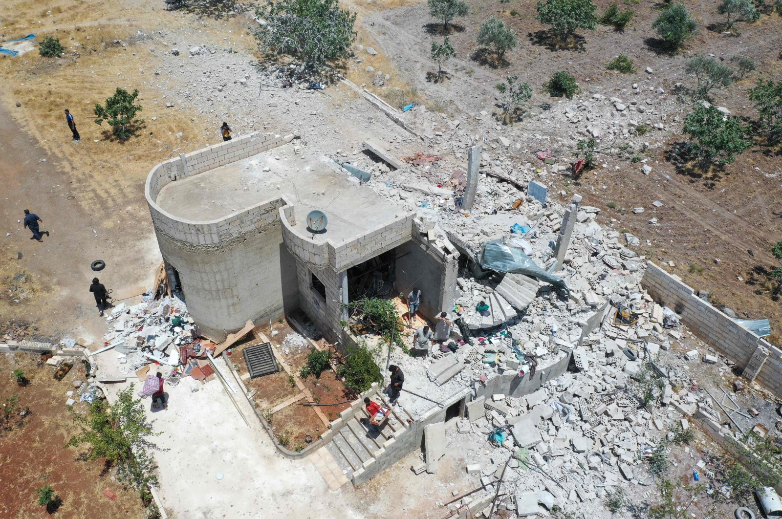 An aerial picture shows people salvaging items from the rubble of a damaged house following reported regime shelling in Jabal al-Zawiya's Balyun village, in the south of Syria's last major opposition stronghold of Idlib in the country's northwest, July 3, 2021. (AFP Photo)