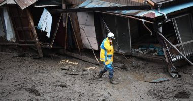 A police officer walks through the mud past a damaged building at the scene of a landslide in Atami, Shizuoka Prefecture, Japan, July 5, 2021. (AP Photo)