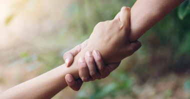 Two hands holding each other in solidarity. (Shutterstock Photo)
