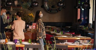 A waiter wearing a face mask and gloves stands in a nearly emptied interior restaurant in Moscow, Russia, July 2, 2021. (AP Photo)