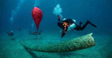 A diver inflates a lifting bag attached to the remains of a fish farm on the seabed, near the island of Ithaca, Greece, June 10, 2021. (Ghost Diving via Reuters)
