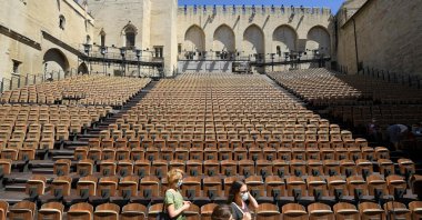People stand in the "Cour d'honneur" of the Popes' Palace (Palais des papes) stage on the first day of this year's edition of the Avignon theatre festival in Avignon, France, July 5, 2021. (AFP Photo)