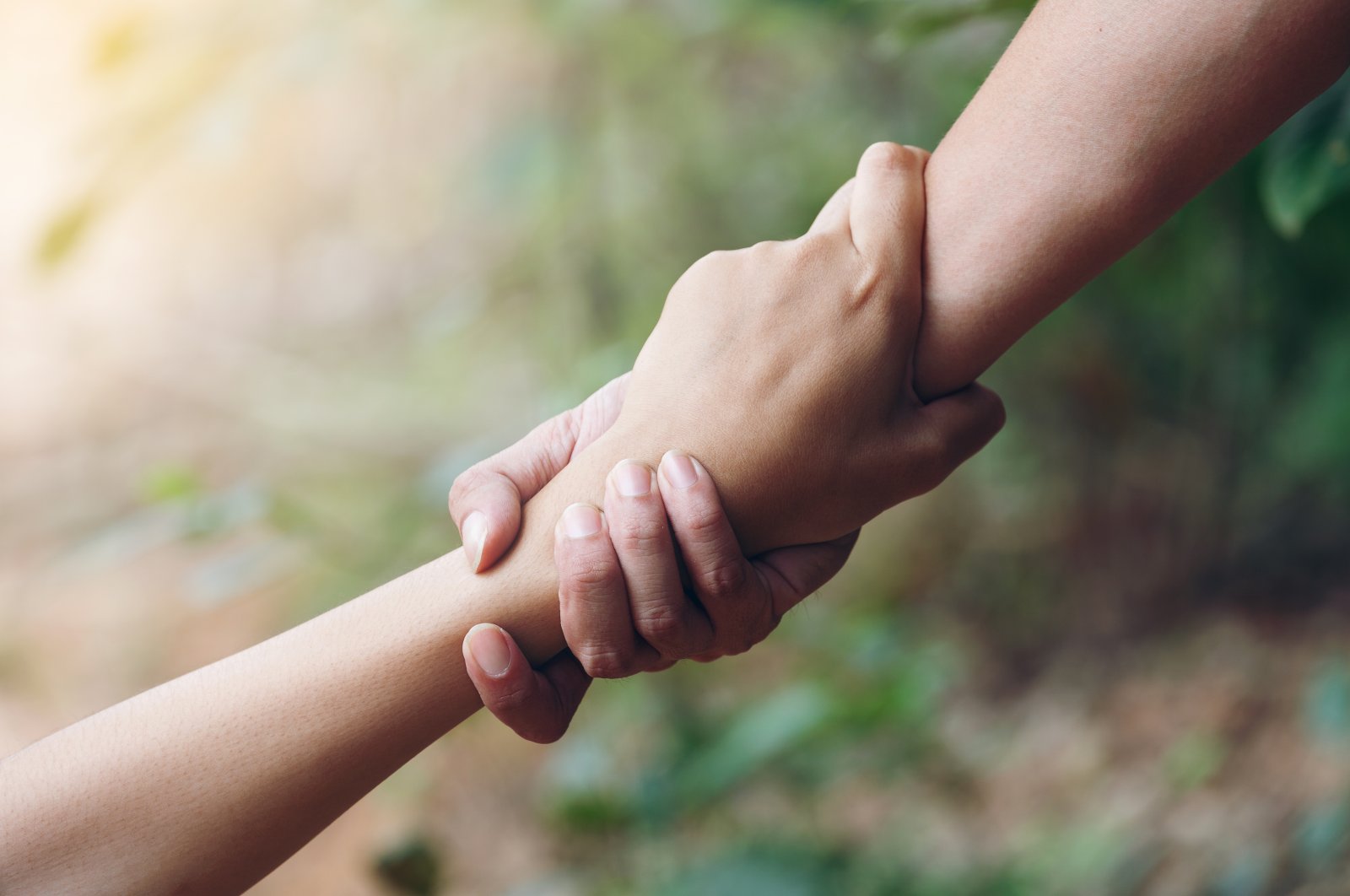 Two hands holding each other in solidarity. (Shutterstock Photo)