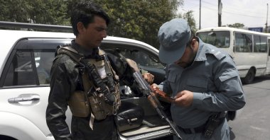 An Afghan police officer checks the documentation of a gun owner, at a temporary checkpoint in Kabul, Afghanistan, July 4, 2021. (AP Photo)