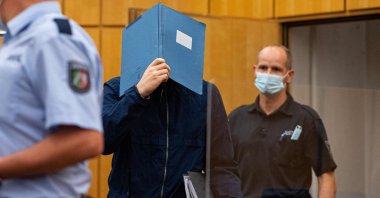 The main defendant (C) hides his face behind a folder as he arrives for his judgement in a child sex abuse case at court in Muenster, northwestern Germany, on July 6, 2021. (AFP Photo)