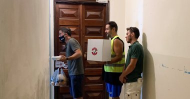 Camille Madi, director of Basecamp, carries a vegan meal a bag of vegetables to distribute to people in need in Beirut, Lebanon, July 1, 2021. (Reuters Photo)