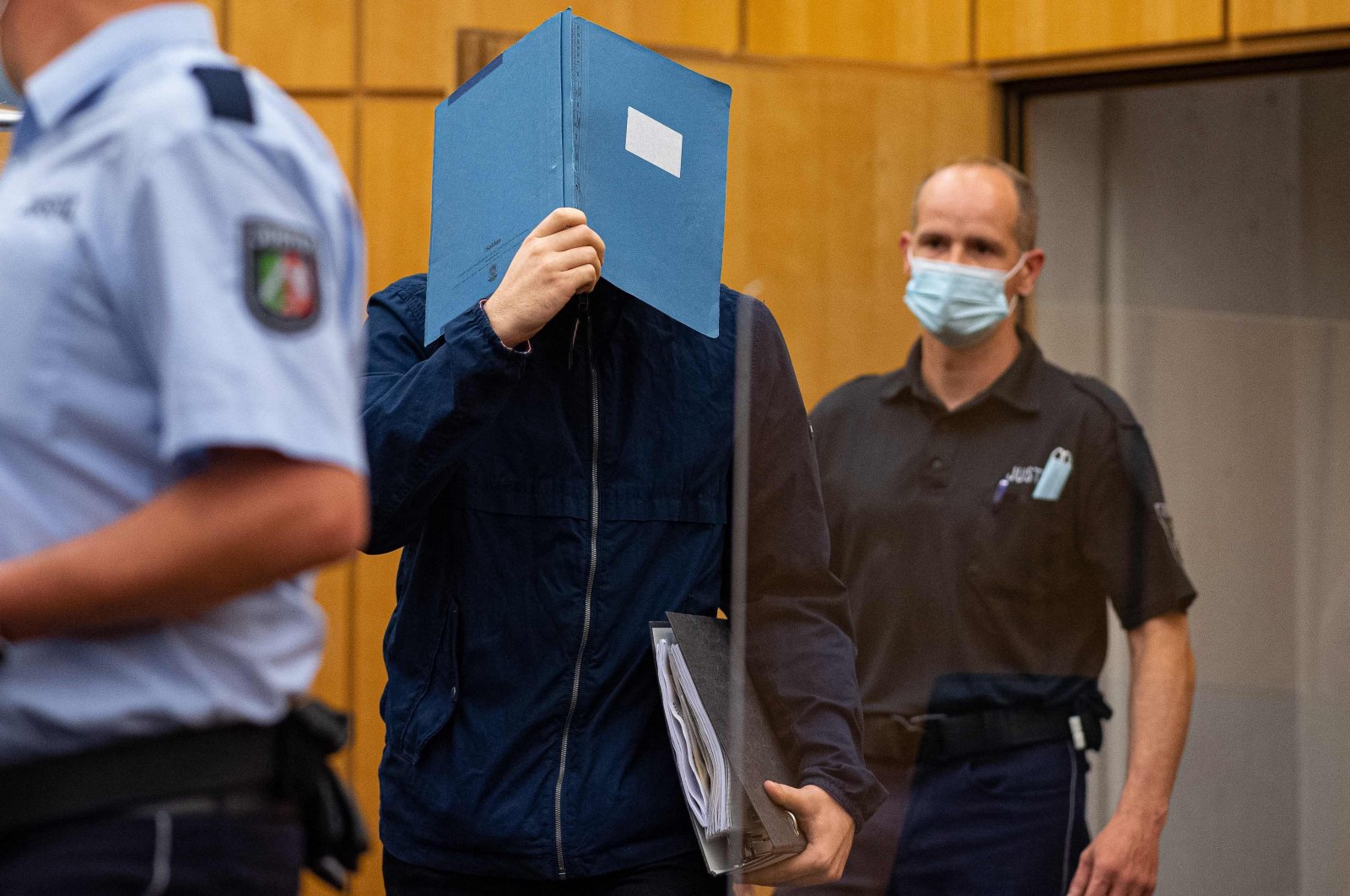 The main defendant (C) hides his face behind a folder as he arrives for his judgement in a child sex abuse case at court in Muenster, northwestern Germany, on July 6, 2021. (AFP Photo)