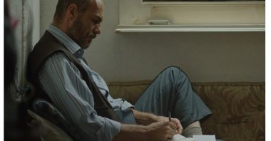 Umut Karadağ takes notes while sitting down, in a scene from the film “Bağlılık Hasan” ("Commitment Hasan"). (Archive Photo)