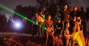 Palestinian protesters use high-powered lasers during a demonstration against the Israeli illegal settlers' outpost of Eviatar, in the town of Beita, near the occupied West Bank city of Nablus, occupied Palestine, July 1, 2021. (AFP Photo)