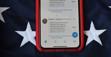 This illustration photo shows a mobile phone placed on a U.S. flag with tweets from then U.S. President Donald Trump masked with warnings imposed by Twitter stating that they may be incorrect, Nov. 5, 2020. (AFP Photo)