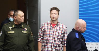 Government officials and Belarusian activist Roman Protasevich (C) enter the press center before a briefing for journalists and diplomats organized by the Ministry of Foreign Affairs of Belarus in Minsk, June 14, 2021. (Photo by STRINGER / AFP)