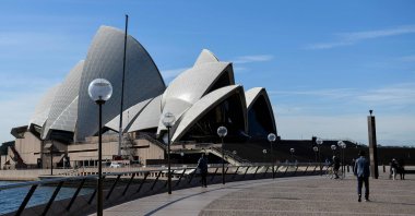 People walk through an unusually quiet Sydney Opera House forecourt as the city remains in lockdown for a second week to contain an outbreak of the highly contagious delta COVID-19 variant, Sydney, Australia, July 6, 2021. (AFP Photo)