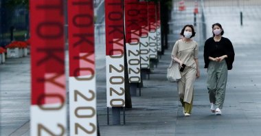 Pedestrians in safety masks against COVID-19 walk past Tokyo 2020 Olympic Games advertising in the Centre Promenade Park, Tokyo, Japan, July 8, 2021. (Reuters Photo)