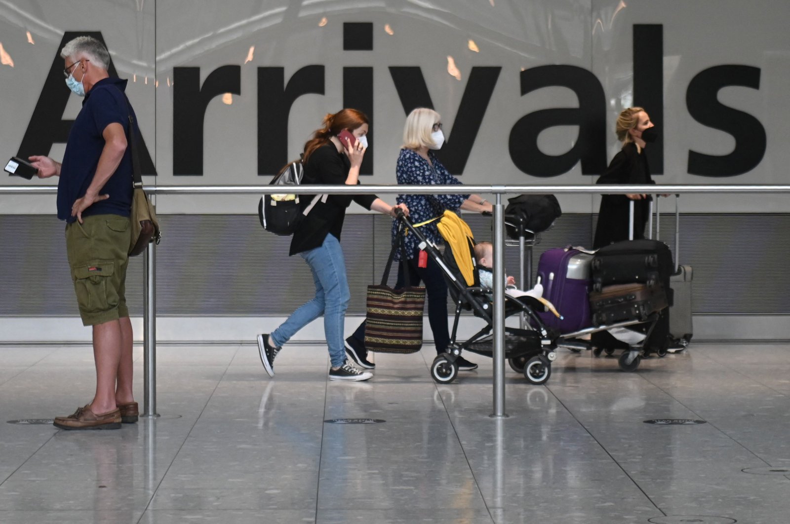 Passengers push their luggage on arrival in Terminal 5 at Heathrow airport, London, June 3, 2021. (AFP Photo)