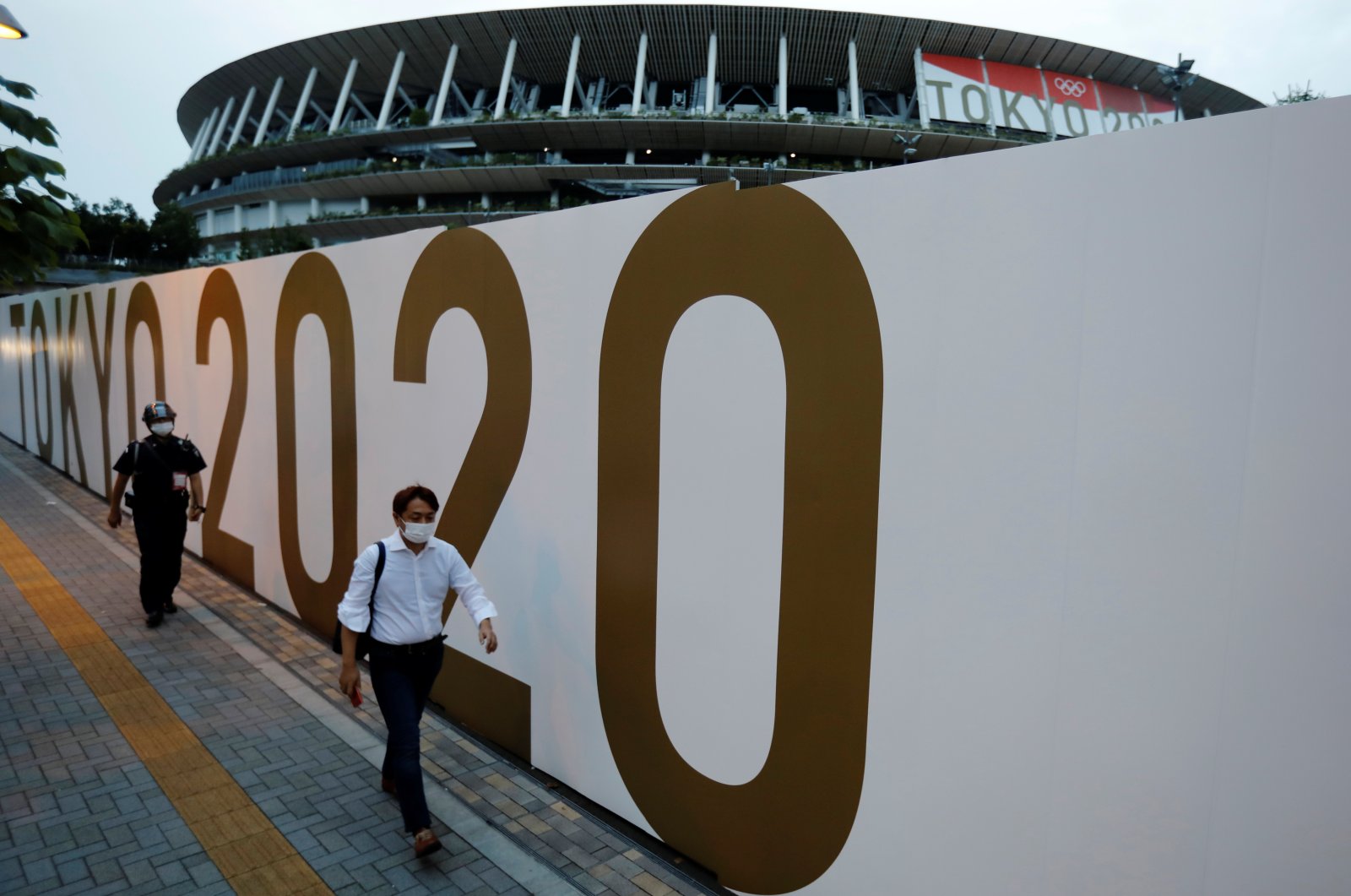 Pedestrians wearing protective masks against COVID-19 walk in front of the National Stadium, the main venue of the Tokyo 2020 Olympics and Paralympics, Tokyo, Japan, July 7, 2021. (Reuters Photo)