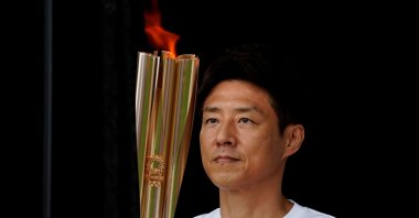 Shuzo Matsuoka, Tokyo's first torchbearer, holds the torch at a lighting ceremony during which torchbearers pass the flame to the next one via a torch kiss, after their relay on a public road was canceled due to the coronavirus pandemic, at the Tokyo 2020 Olympic torch relay celebration in Tokyo, Japan, July 9, 2021. (Reuters Photo)