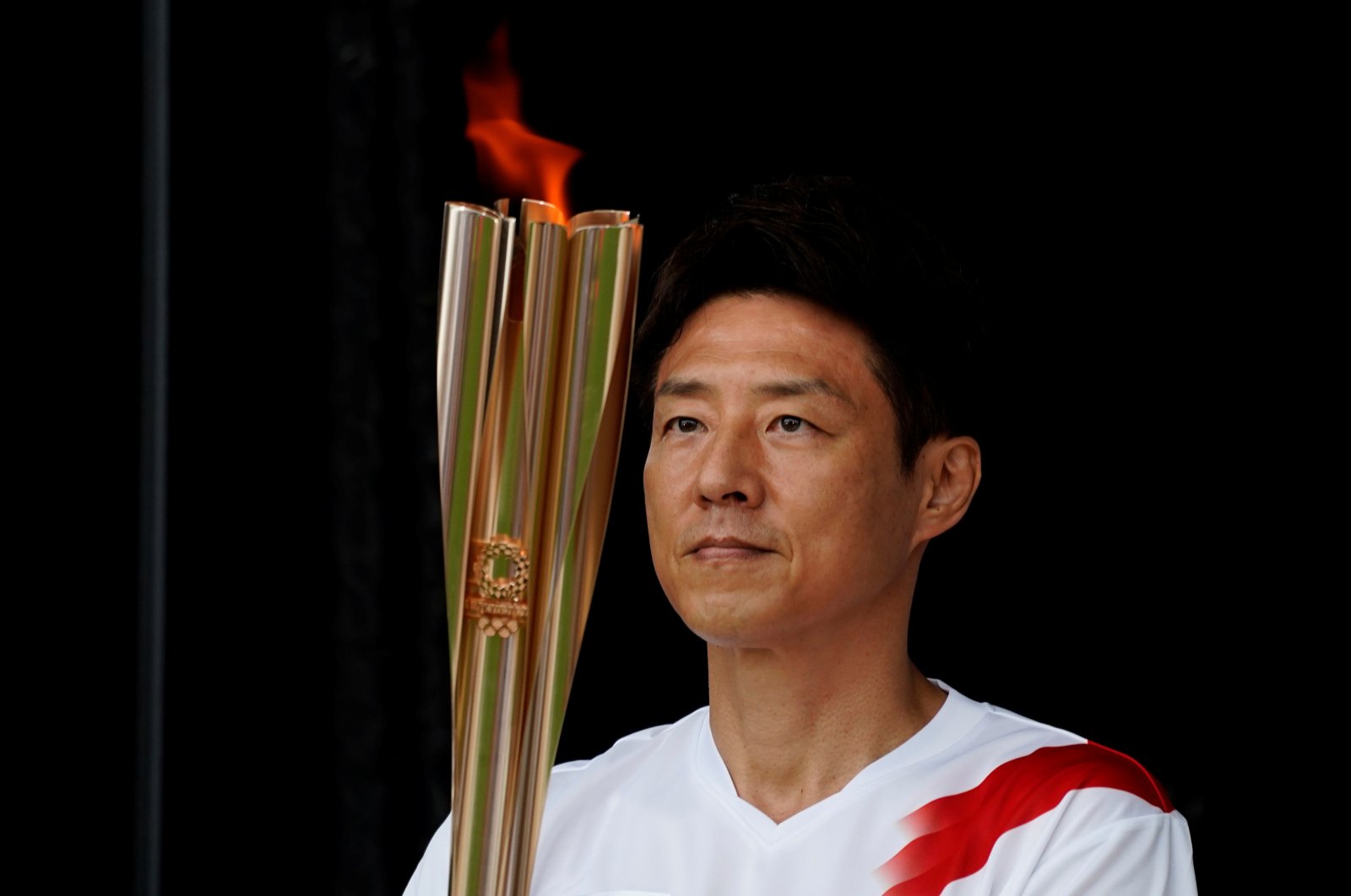 Shuzo Matsuoka, Tokyo's first torchbearer, holds the torch at a lighting ceremony during which torchbearers pass the flame to the next one via a torch kiss, after their relay on a public road was canceled due to the coronavirus pandemic, at the Tokyo 2020 Olympic torch relay celebration in Tokyo, Japan, July 9, 2021. (Reuters Photo)