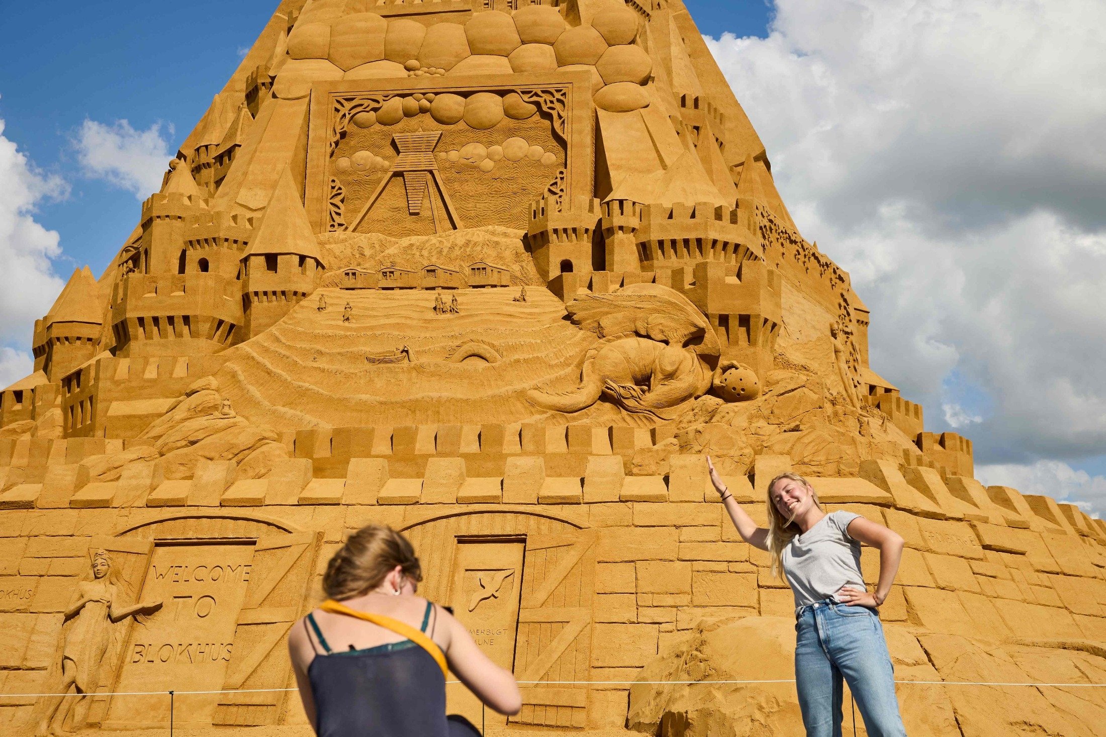 People pose for photos by the world's tallest sand sculpture, under construction in Blokhus, Denmark, July 7, 2021. (AFP Photo)