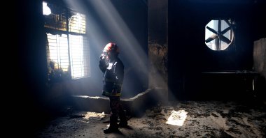 A firefighter communicates with his colleagues on a walkie-talkie inside the burnt food and beverage factory in Rupganj, outside Dhaka, Bangladesh, July 9, 2021. (AP Photo)