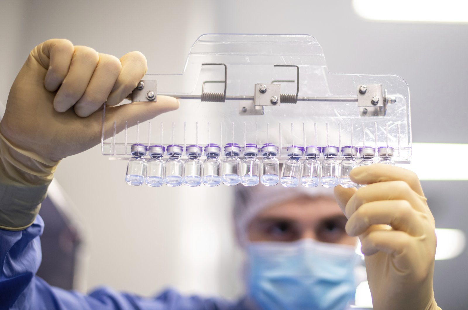 A technician inspects filled vials of the Pfizer-BioNTech COVID-19 vaccine at the company's facility in Puurs, Belgium, March, 2021. (Pfizer via AP)