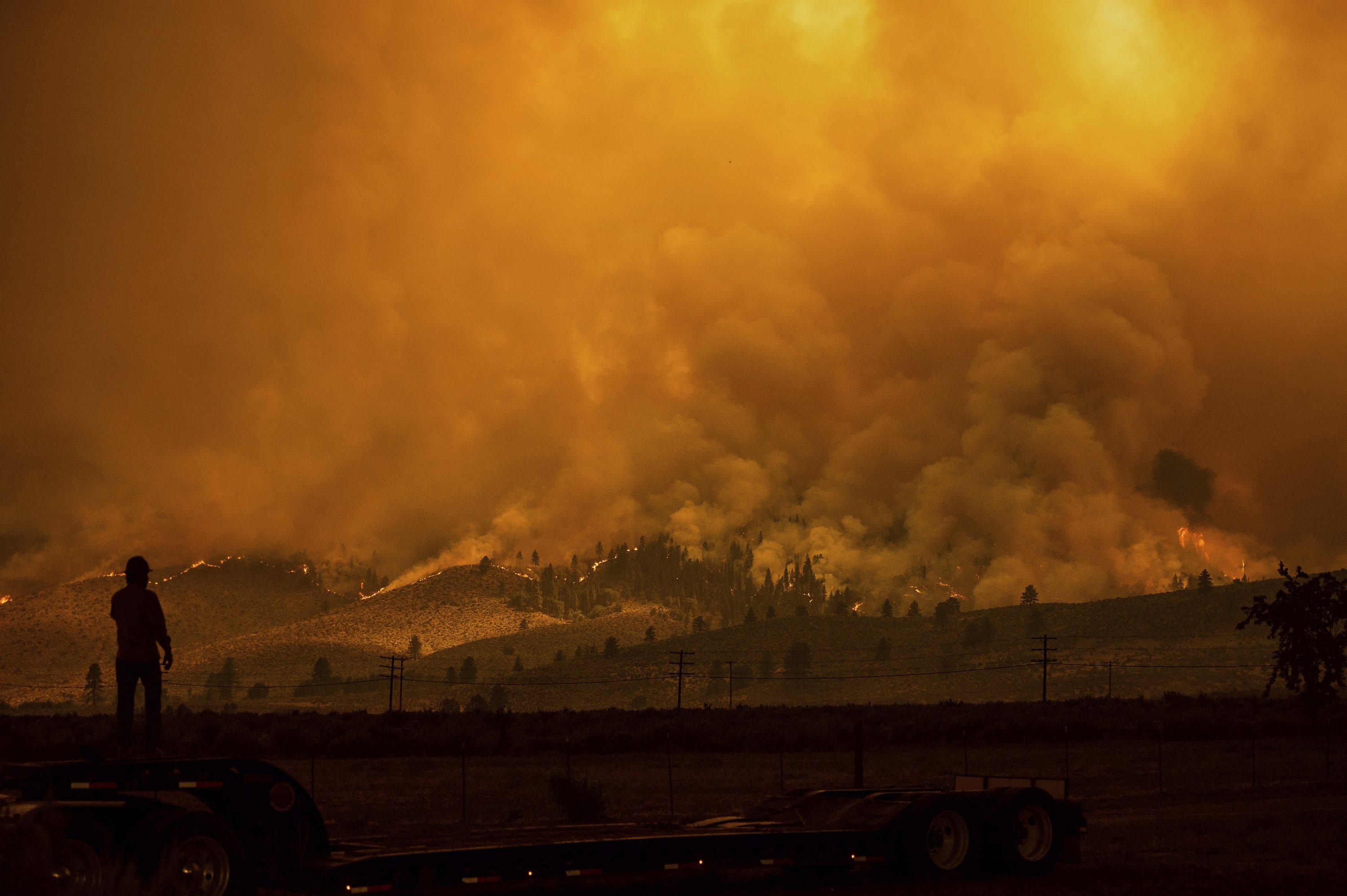 A truck driver watches as the Sugar Fire, part of the Beckwourth Complex Fire, burns in Doyle, California, U.S., July 10, 2021. (AP Photo)