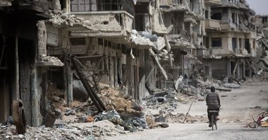 In this June 5, 2014 file photo, a man rides a bicycle through a devastated part of Homs, Syria. (AP Photo)