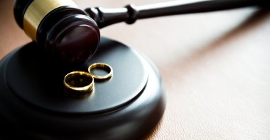 Two wedding rings rest near a judge's gavel. (Getty Photo)
