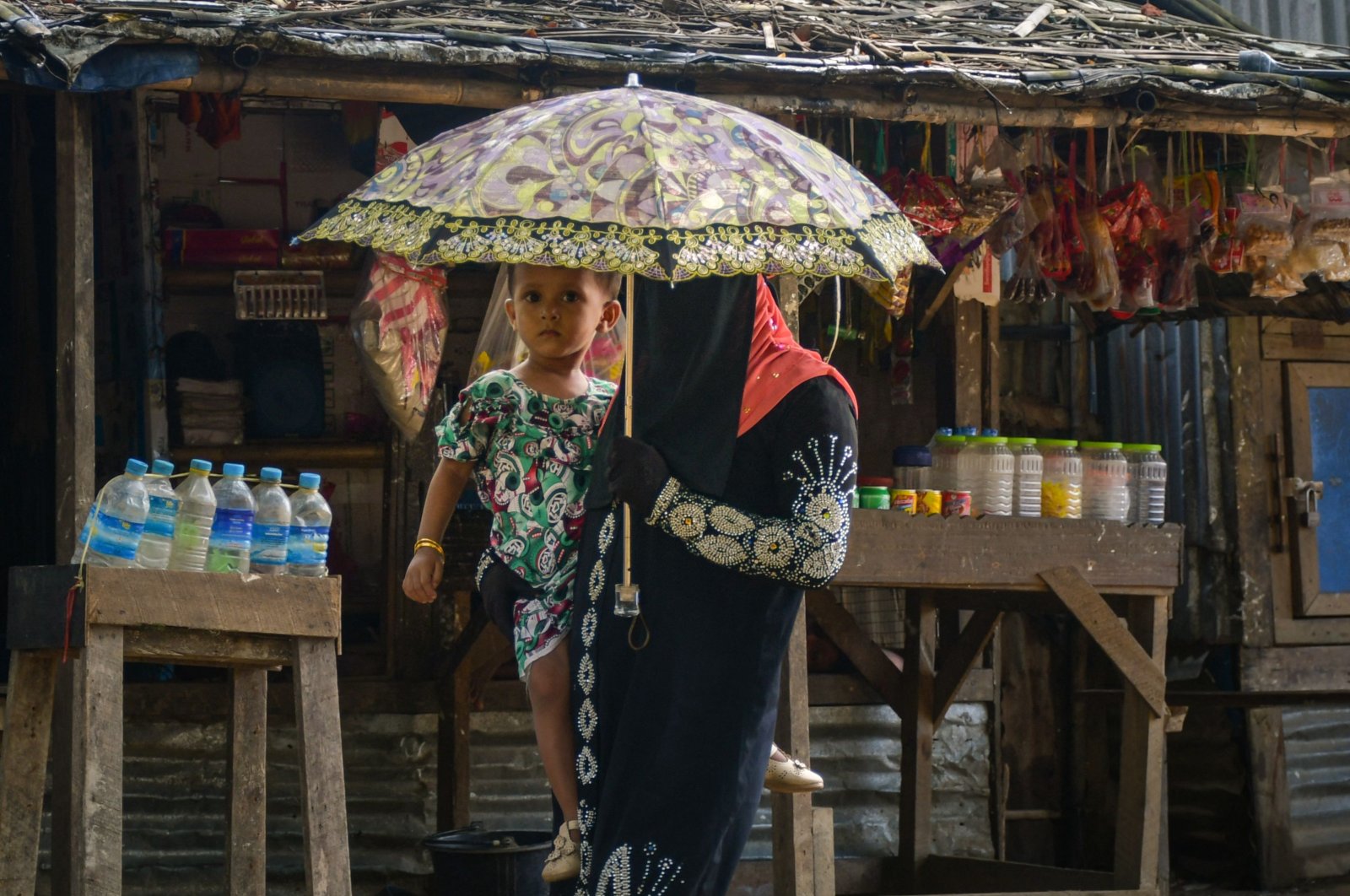A member of the internally displaced Rohingya Muslim community carries a child as she walks through the Thet Kay Pyin camp in Sittwe, Myanmar, June 5, 2021. (AFP Photo)