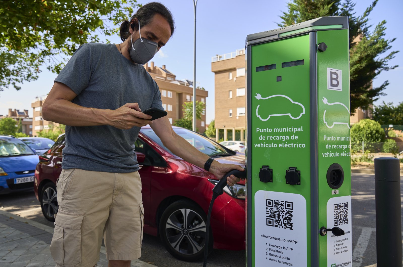 A man charges his electric car at an electrical charging point in Rivas Vaciamadrid, Spain, June 15, 2021. (AP Photo)