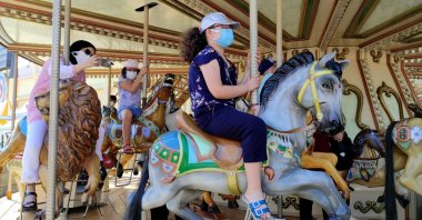 People wearing protective masks ride a carousel at an amusement park in Istanbul, Turkey, July 10, 2021. (AA PHOTO) 