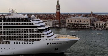 Tugboats escort the MSC Orchestra cruise ship across the basin past the Bell Tower and the Doge's palace as it leaves Venice, Italy, June 5, 2021. (AFP Photo)