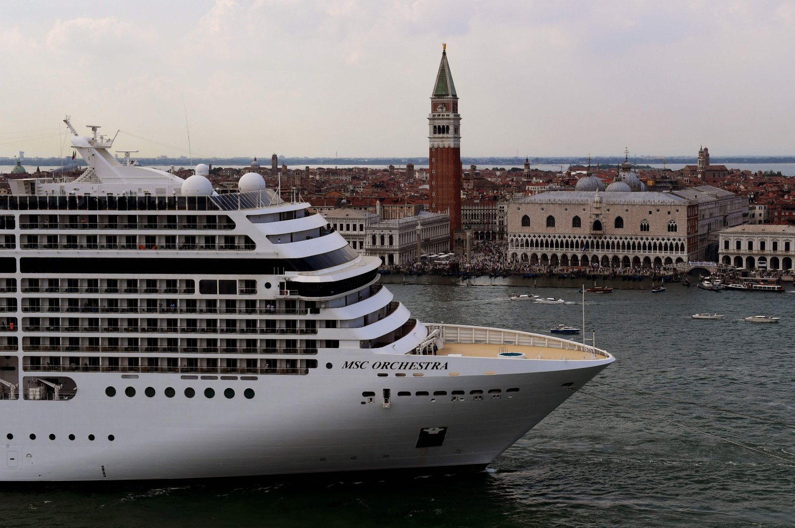 Tugboats escort the MSC Orchestra cruise ship across the basin past the Bell Tower and the Doge's palace as it leaves Venice, Italy, June 5, 2021. (AFP Photo)