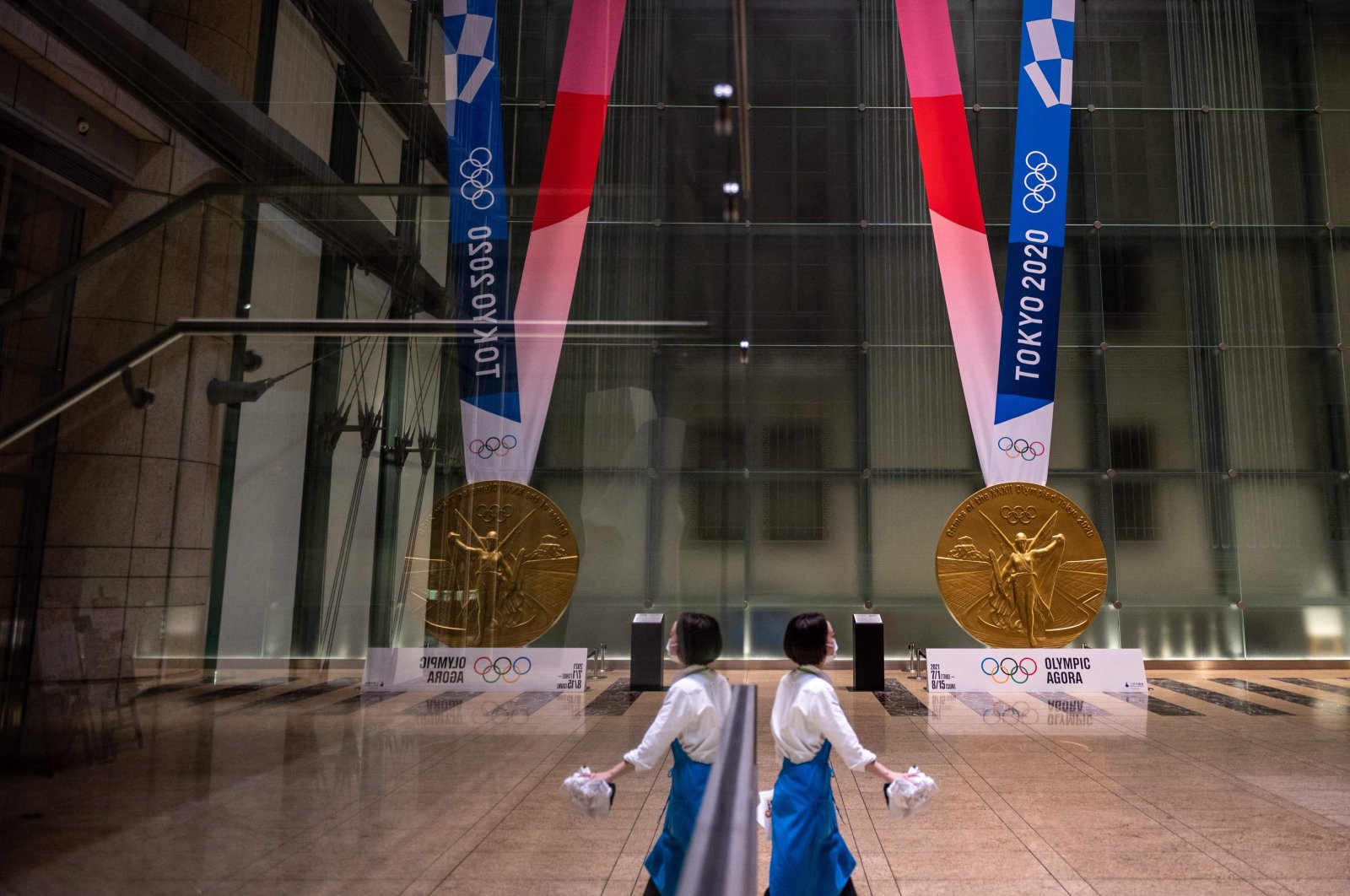 A woman walks near a large-scale reproduction of the Tokyo 2020 Olympic Games gold medal as part of the Olympic Agora event at Mitsui Tower, Tokyo, Japan, July 14, 2021. (AFP Photo)