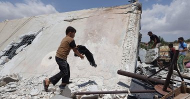 A young boy salvages belongings from a house destroyed by a Russian missile attack in the Jabal al-Zawiya region in the south of Syria's opposition-held Idlib province, on July 4, 2021. (AFP Photo)