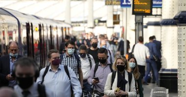 People wear face masks to curb the spread of the coronavirus as they disembark from a train during the morning rush hour at Waterloo train station in London, UK, July 14, 2021. (AP Photo)