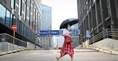 A woman walks past an office building in Beijing, China, July 15, 2021. (AFP Photo)