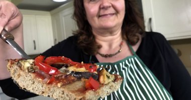 Tiziana di Costanzo, co-founder of Horizon Insects, holds up a slice of pizza made with cricket powder, in her London kitchen, London, U.K., June 2, 2021. (AP Photo)