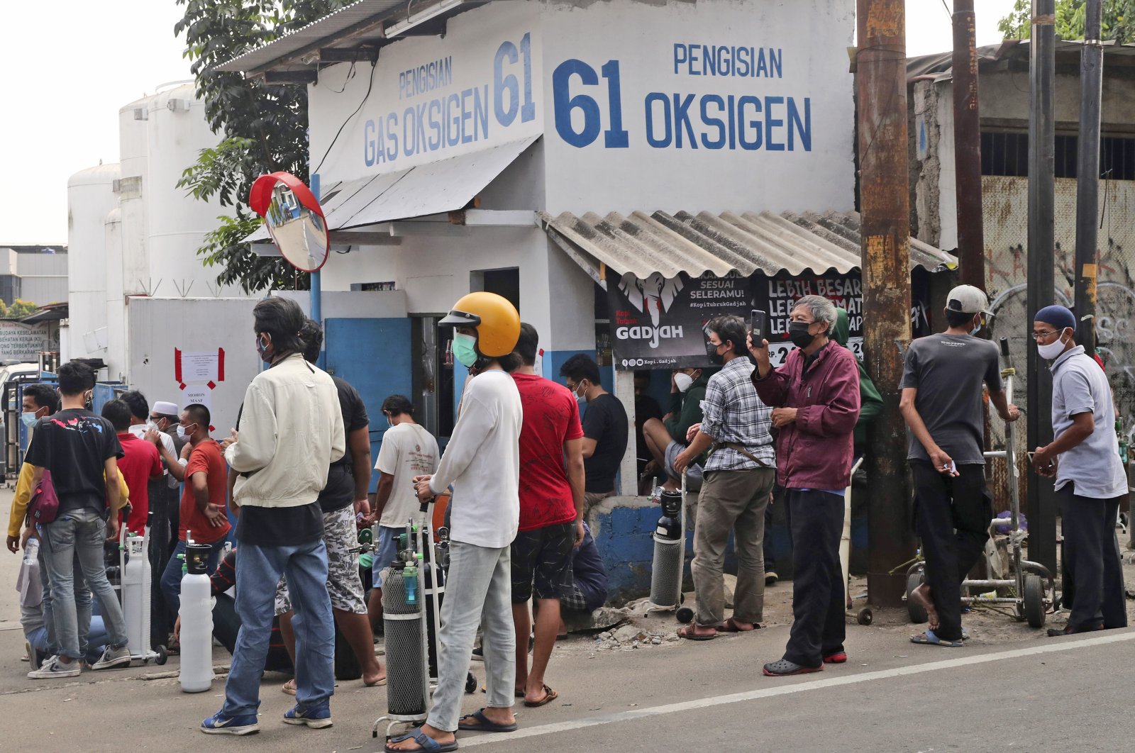People wait for their turn to refill their oxygen tanks at a recharging station in Jakarta, Indonesia, Friday, July 9, 2021. (AP Photo)