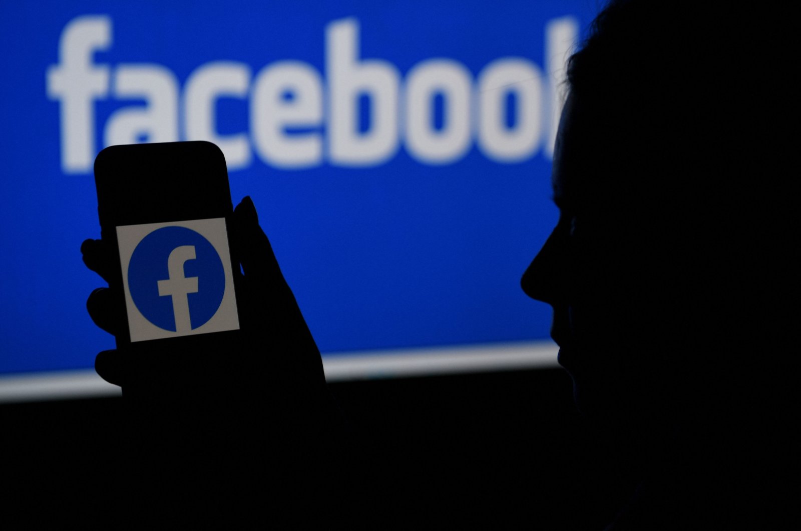A smartphone screen displays the logo of Facebook on a Facebook website background, in Arlington, Virginia, April 7, 2021. (AFP Photo)