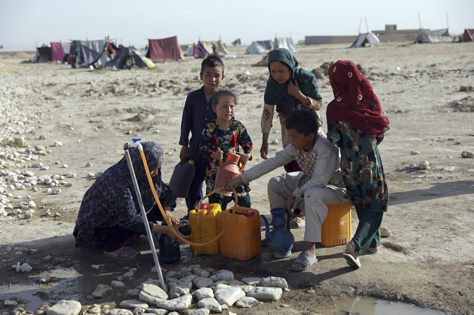 Internally displaced Afghans, who fled their home due to fighting between the Taliban and Afghan security personnel, fill water containers from a public water tap at a camp on the outskirts of Mazar-e-Sharif, northern Afghanistan, July 8, 2021. (AP Photo)