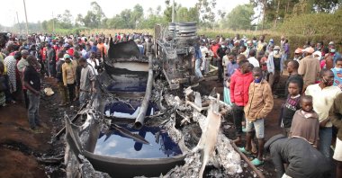 People stand next to a burnt-out petrol tanker that burst into flames when it overturned in western Kenya, while a crowd thronged to collect the spilling fuel, July 18, 2021. (AFP Photo)